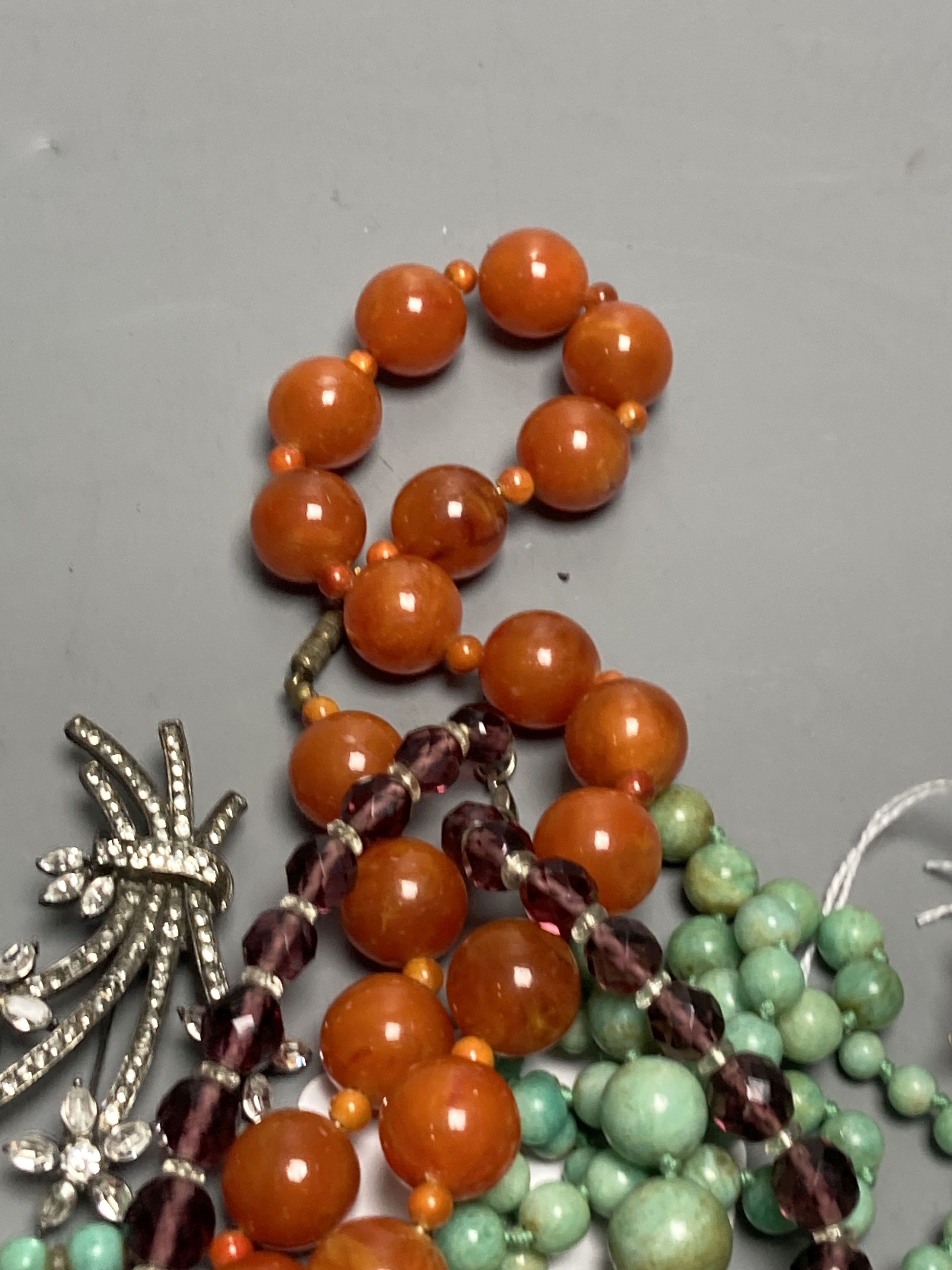 A turquoise bead necklace and pair of earrings, two other necklaces and two brooches including Indian? paste set.